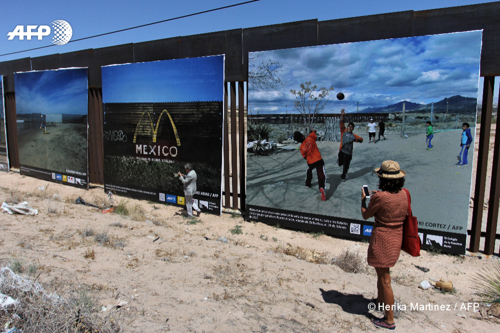 Una mujer asiste a la inauguración de una exposición de diez imágenes de AFP sobre la vida en la frontera entre México y Estados Unidos colocada en la valla metálica que separa Ciudad Juárez, México y Sunland Park, Estados Unidos, en el Puerto de Anapra, Ciudad Juárez, México, el 4 de mayo de 2018.