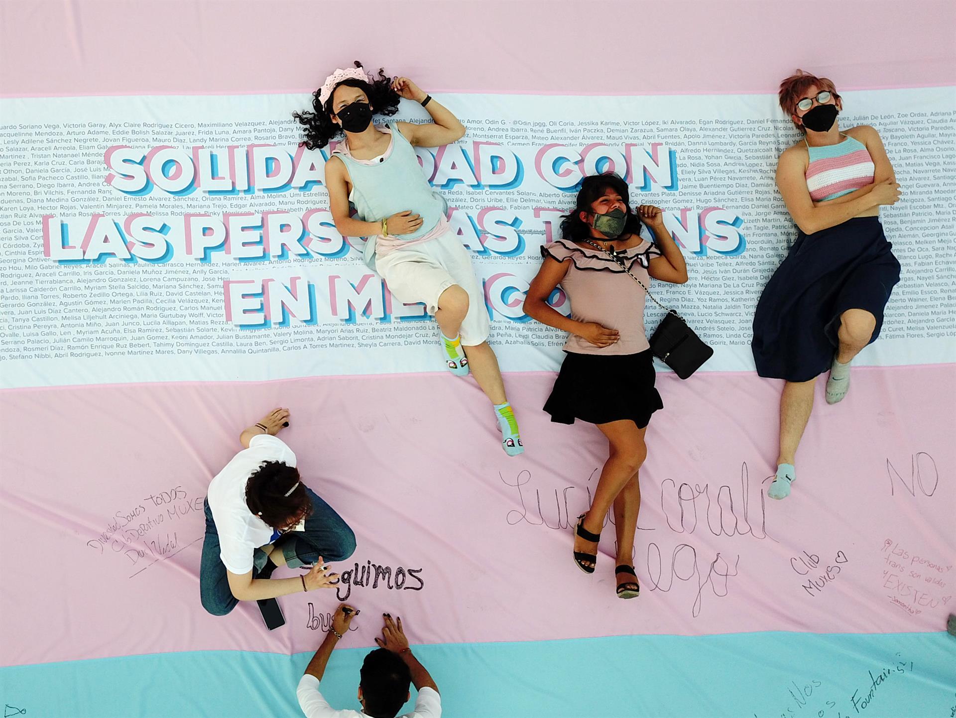 Fotografía aérea que muestra activistas y simpatizantes de la comunidad Trans mientras colocan una bandera gigante con mensajes de apoyo en el Monumento a la Revolución de Ciudad de México. Foto: EFE/Isaac Esquivel