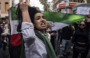 FOTO REFERENCIAL - Una mujer sujeta su pelo a la vez que los manifestantes sujetan una bandera anterior a la Revolución Islámica de Irán durante una protesta a las afueras del Consulado iraní tras la muerte de Mahsa Amini. Crédito: EFE.