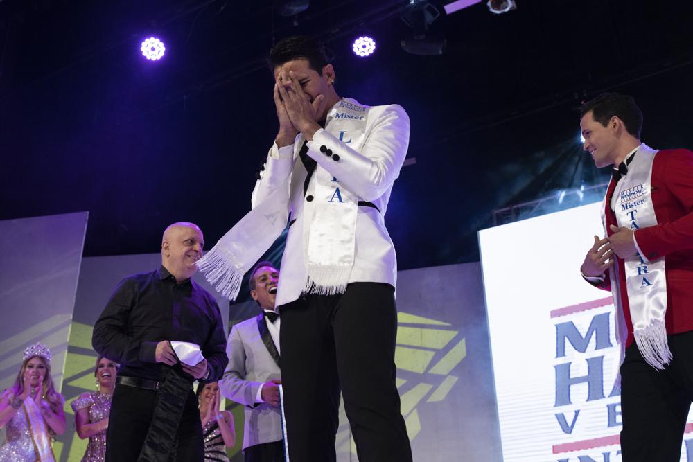 Rafael Sánchez, en representación del estado Lara, en el centro, reacciona luego de que fue anunciado como Míster Handsome Venezuela durante el certamen de belleza masculina en Caracas, Venezuela, el sábado 30 de octubre de 2021. El certamen se llevó a cabo después de que la edición del año pasado fue cancelada debido a la pandemia de COVID-19. (Foto AP/ Ariana Cubillos)