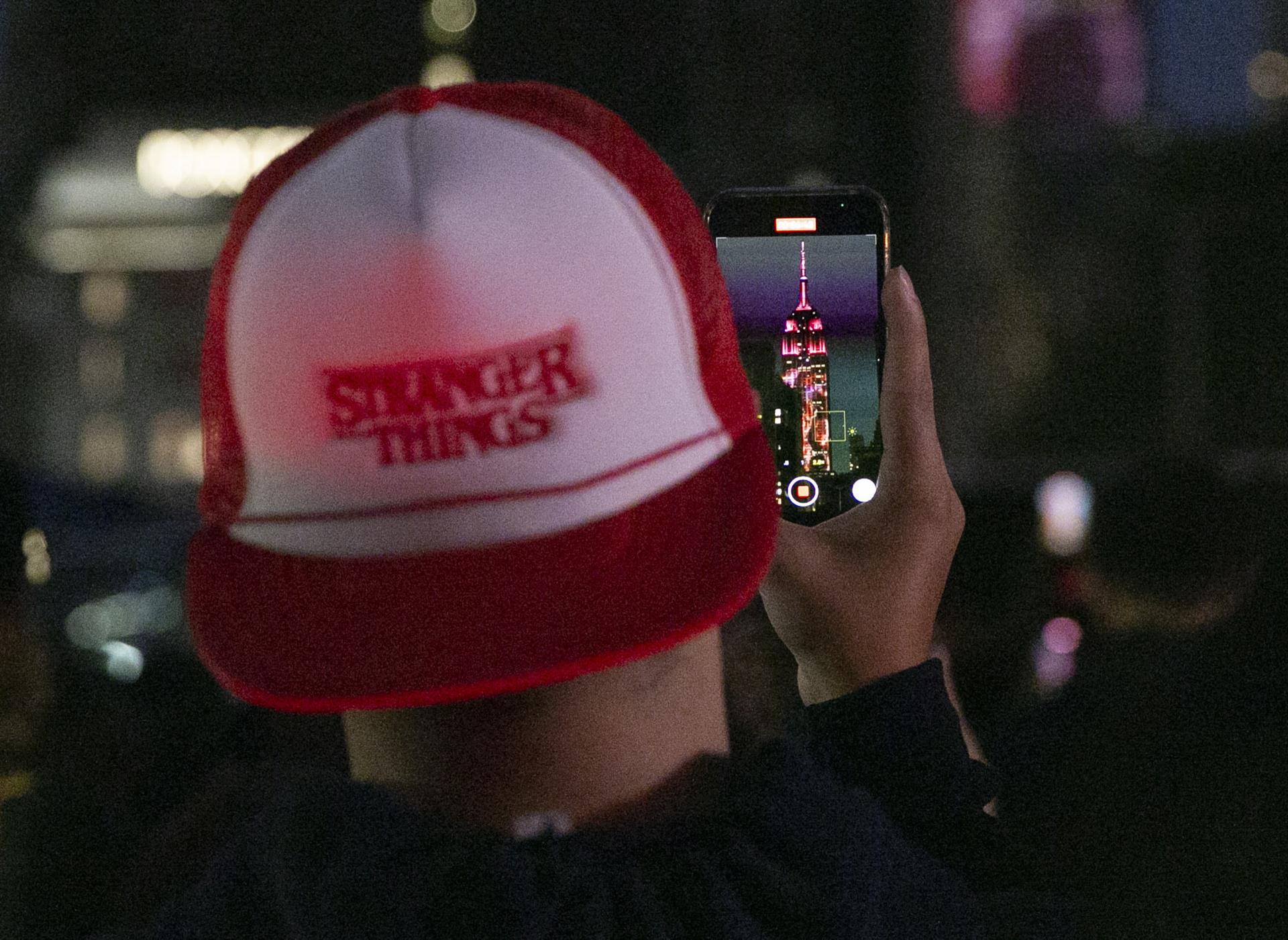Nueva York (Estados Unidos), 27/05/2022.- Un miembro de la multitud graba un espectáculo de video de las historias de la temporada 4 de Stranger Things que se proyecta en el Empire State Building en Nueva York, Nueva York, Estados Unidos, el 26 de mayo de 2022. La esperada temporada 4 de la exitosa serie se estrenará en dos volúmenes el 27 de mayo de 2022. (Estados Unidos, Nueva York) EFE/EPA/SARAH YENESEL