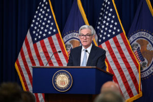 El presidente de la Reserva Federal (FED, en inglés) de Estados Unidos, Jerome Powell, responde a las preguntas de los periodistas detrás de un podio con el sello del Consejo de Gobernadores frente a un fondo azul con banderas estadounidenses y banderas con sellos del Consejo de Gobernadores. Foto: Twitter @federalreserve.